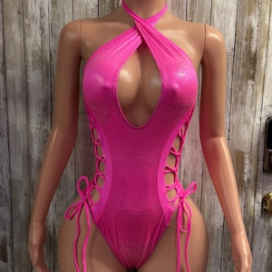 May include: Hot pink one-piece swimsuit with a halter neckline and a keyhole cutout. The swimsuit features a snakeskin pattern and lace-up detailing on the sides. The swimsuit is displayed on a mannequin.