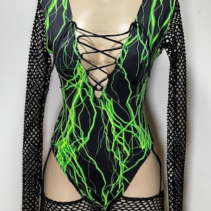 May include: Black bodysuit with a green lightning bolt print and a lace-up front. The bodysuit has leg cutouts and is paired with black fishnet sleeves and thigh-highs.