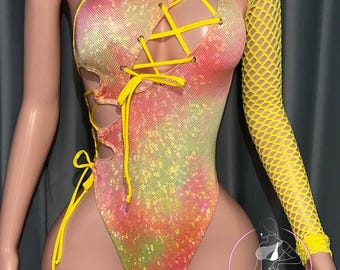 May include: A one-shoulder bodysuit in a vibrant, sequined fabric with a gradient of yellow, orange, and pink. It features a lace-up design on the front and a fishnet sleeve. The bodysuit is a unique piece of apparel.