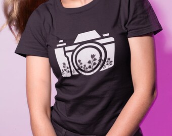 May include: A black t-shirt with a white silhouette of a camera with flowers inside the lens.