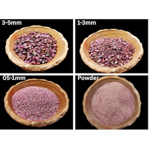 May include: Four wooden bowls containing pink gemstones of varying sizes. The bowls are labelled with the sizes: 3-5mm, 1-3mm, 0.5-1mm, and Powder. The gemstones range from small chips to a fine powder.