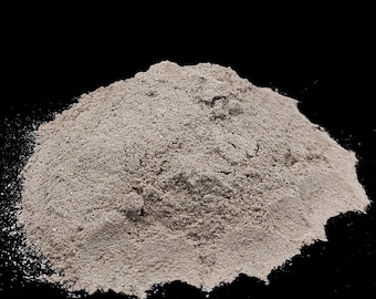 May include: A pile of light gray powder against a black background. The powder has a fine, granular texture and appears to be a bulk ingredient. The image is a close-up shot, highlighting the texture and color of the powder.