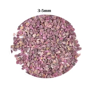 Op de afbeelding: Een close-up afbeelding van een stapel kleine, roze robijn edelsteen chips, variërend in grootte van 3 tot 5 millimeter. De chips zijn onregelmatig gevormd en hebben een licht ruwe textuur.
