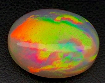 May include: A white oval opal gemstone with a rainbow of colors, including green, orange, and red.