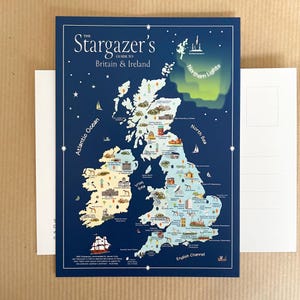 May include: A dark blue postcard titled The Stargazer's Guide to Britain & Ireland featuring a map of the British Isles. The map includes illustrations of observatories, telescopes, and the Northern Lights, with text labels for oceans and seas.