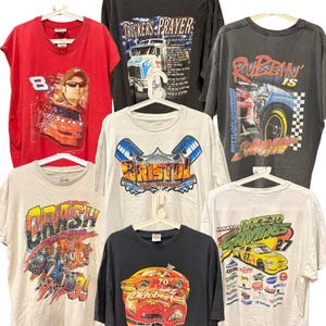 Könnte beinhalten: Sammlung von Vintage-Grafik-T-Shirts mit Rennmotiven. Die Shirts sind in verschiedenen Farben erhältlich, darunter Rot, Schwarz und Weiß, mit Designs, die Rennwagen, Logos und Text enthalten. Einige Shirts tragen die Aufschrift "BRISTOL" und "RACE TO SAVINGS".