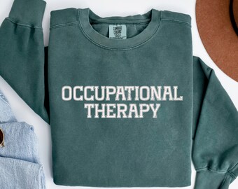 May include: A dark green sweatshirt with the text "OCCUPATIONAL THERAPY" in white lettering. The sweatshirt is made of a soft, comfortable material.