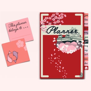 May include: A red planner with a Japanese-inspired design featuring a pagoda and cherry blossoms. The planner has a tabbed index with months of the year printed on each tab. The cover also includes the text "Planner".