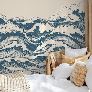 May include: A wall mural featuring a stylized illustration of ocean waves in shades of blue against a cream background. The waves are depicted with detailed lines, creating a sense of movement and depth. A straw hat and a beige blanket are on the bed.