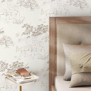 May include: Off-white wallpaper with a repeating pattern of deer, trees, and foliage in shades of gray and brown. A wooden headboard and pillows are visible on the right side of the image. A small side table holds glasses and a book.