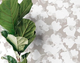 Op de afbeelding: Een close-up van een vioolbladplant met grote, groene bladeren. De achtergrond heeft een herhalend patroon van witte bloemvormen op een neutrale, taupekleurige achtergrond. De afbeelding combineert natuurlijke en abstracte elementen.