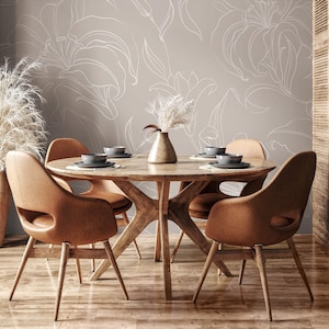 May include: A round wooden dining table with four brown leather chairs. The table has a natural wood finish and the chairs have a simple, modern design. The wall behind the table is painted a light gray and features a white floral pattern.