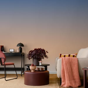 May include: A modern living room scene with a color gradient wall. The room features a black desk, a red chair, a sofa with a throw blanket, and a coffee table with a plant and decorative items. The color palette includes shades of red, brown, and blue.