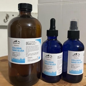 May include: Three bottles of colloidal nano silver solution. The bottles are labeled "Mountain View Holistics" and "Colloidal Nano Silver". The bottles are in different sizes, with the largest bottle being brown glass and the two smaller bottles being blue glass.