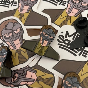 May include: A set of four enamel pins featuring a cartoon character wearing a mask. The pins are in various colors, including black, white, green, and yellow. The pins are on a white background with the text "My School" written in black.