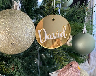 May include: Gold round Christmas bauble with the name "David" written in white cursive lettering.