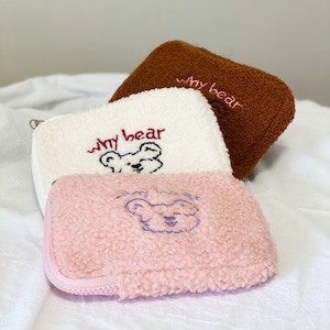 May include: Three fuzzy zippered pouches with embroidered teddy bears and the text "my bear". The pouches are brown, white, and pink.