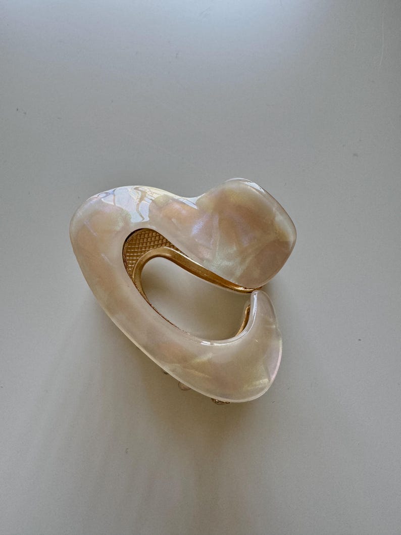May include: A white and gold heart-shaped hair clip with a pearlescent finish.