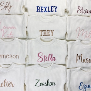 May include: A collection of white knit sweaters, each embroidered with a different name in various colors. The names include "Eddy", "Rexley", "Storm", "Lennon Kate", "Trey", "Mil", "Jameson", "Stella", "Mason", "Zeeshan", and "Ezia".