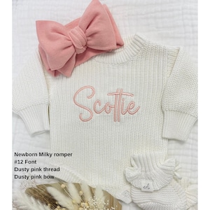 May include: A newborn milky romper with the name "Scottie" embroidered in dusty pink thread. The outfit includes a matching dusty pink bow headband and a pair of ruffled booties. The text on the image reads: Newborn Milky romper, #12 Font, Dusty pink thread, Dusty pink bow.
