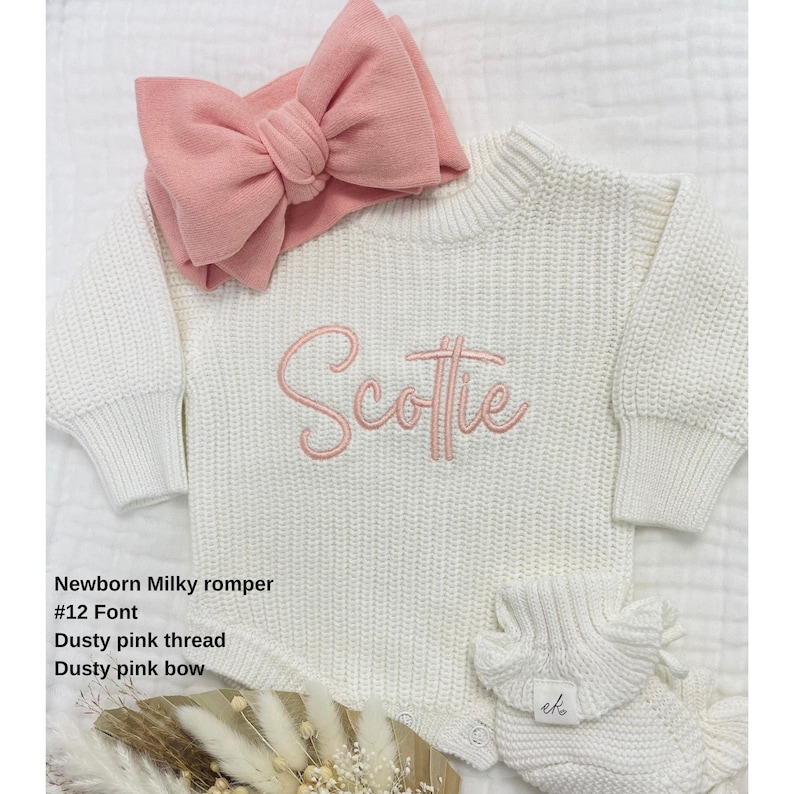 May include: A newborn milky romper with the name "Scottie" embroidered in dusty pink thread. The outfit includes a matching dusty pink bow headband and a pair of ruffled booties. The text on the image reads: Newborn Milky romper, #12 Font, Dusty pink thread, Dusty pink bow.