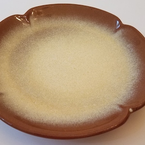 May include: A brown ceramic plate with a scalloped edge and a light yellow glaze.