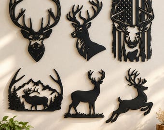 May include: A collection of six black wall art pieces featuring deer silhouettes. Designs include a deer head, a profile view, a deer head overlaid on an American flag, a deer in a mountain landscape, a standing deer, and a leaping deer silhouette.