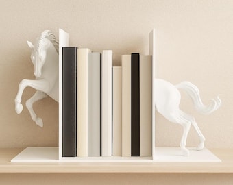 Könnte beinhalten: Weiße Pferde-Buchstützen mit einem Regal, das eine Reihe von Büchern enthält. Die Buchstützen zeigen ein sich aufbäumendes Pferdedesign. Die Bücher haben verschiedene Farben, darunter Schwarz, Weiß und Beige. Das Regal ist aus Holz.