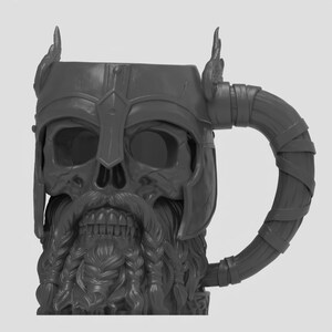 May include: A dark gray mug shaped like a skull wearing a winged helmet. The skull features a detailed beard with braided sections and a mustache. The handle is designed to resemble a wrapped or bound material, extending from the side of the helmet.