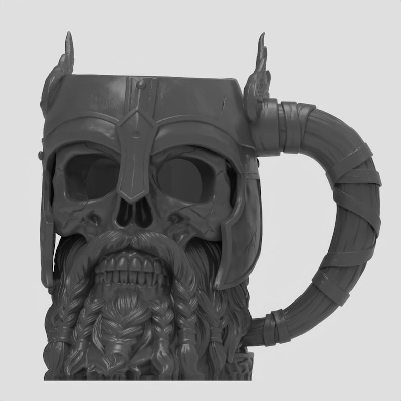 May include: A dark gray mug shaped like a skull wearing a winged helmet. The skull features a detailed beard with braided sections and a mustache. The handle is designed to resemble a wrapped or bound material, extending from the side of the helmet.