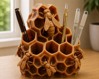 May include: A brown honeycomb-shaped desk organizer made of wax, featuring multiple hexagonal compartments and sculpted bees attached to the exterior. Four pens are inserted into the various openings of the structure.