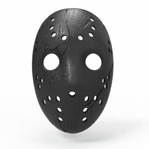 Könnte beinhalten: Eine schwarze Hockeymaske mit zahlreichen kleinen, gleichmäßig verteilten Löchern und zwei großen Augenöffnungen. Die Maske hat eine strukturierte Oberfläche mit feinen Rissen und Markierungen. Die Gesamtform ist oval, mit einem leicht gebogenen Design.
