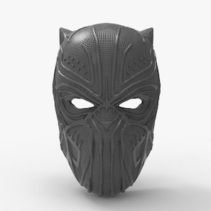Könnte beinhalten: Eine schwarze Maske mit strukturierter Oberfläche, mit Augenöffnungen und detailliertem Design. Die Maske hat spitze Ohren und ein geformtes Aussehen, das einem Superhelden oder einer Comicfigur ähnelt.