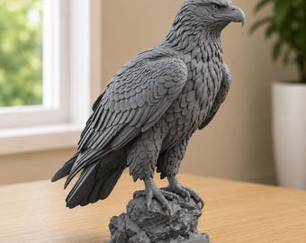 May include: A monochromatic gray eagle figurine standing on a textured rock base. The sculpture features detailed feather patterns across the wings and body, with the eagle looking toward the right. The base includes a small, blank rectangular plaque.