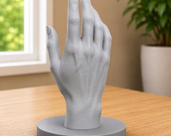 May include: A matte light gray hand-shaped display stand featuring a realistic anatomical design with visible knuckles, tendons, and fingernails. The hand is mounted vertically on a circular base of the same color, providing a stable structure.