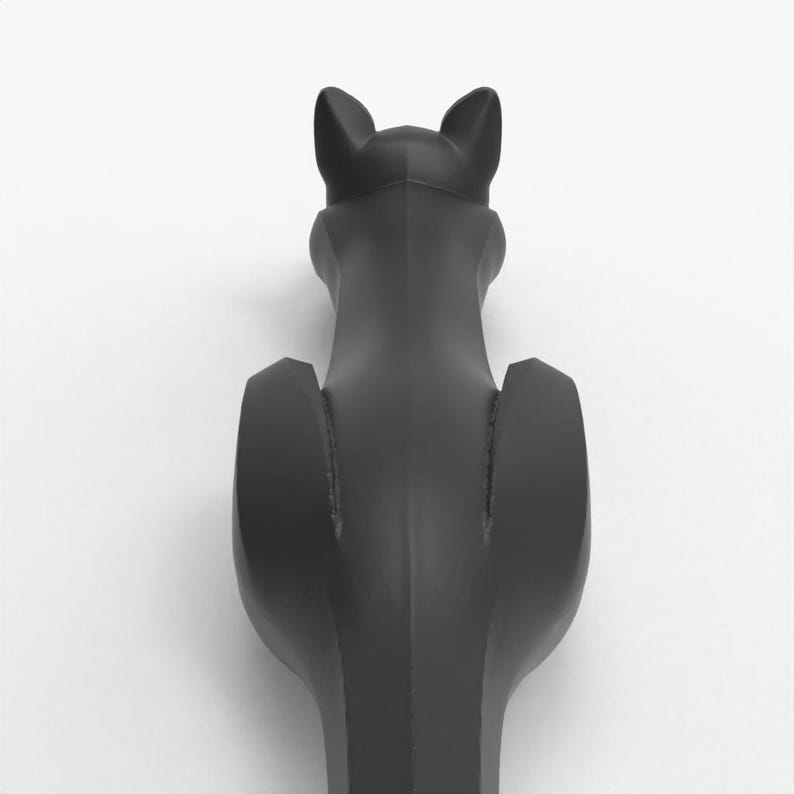 May include: A black cat-shaped bottle stopper, viewed from the back. The stopper has a sleek, matte finish and features pointed ears and a stylized body. The design is minimalist and modern, suitable for wine bottles.