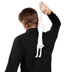 Może przedstawiać: Biała, stylizowana rzeźba kota trzymana przez osobę. Rzeźba kota jest wydłużona i ma prosty, minimalistyczny design. Osoba ma na sobie czarną koszulę z długim rękawem.