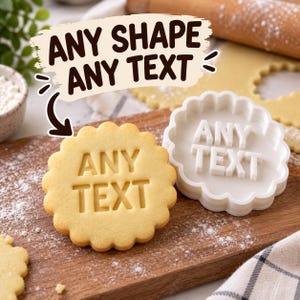 May include: A white scalloped cookie cutter with the embossed text ANY TEXT, positioned next to a round cookie featuring the same scalloped edge and the indented text ANY TEXT, both resting on a wooden surface with scattered flour.