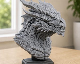 May include: A gray dragon bust sculpture featuring intricate scale textures, sharp horns, and a detailed snout with visible teeth. The creature is depicted in a side profile view, mounted on a solid, dark gray hexagonal base, showcasing a high level of craftsmanship in the molded surface details.