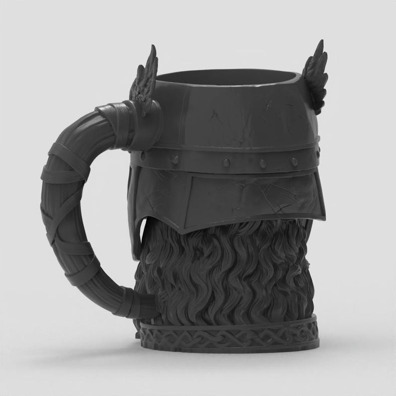 May include: A matte black mug shaped like a helmeted head with winged accents on the sides. The handle is textured to resemble wrapped leather strips, while the base features an intricate braided pattern and the body displays wavy hair details.