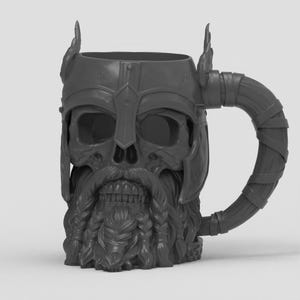 May include: A dark gray mug shaped like a skull wearing a winged helmet. The skull features a detailed beard with braided sections and a mustache. The handle of the mug is designed to look like a wrapped or bound piece of material or leather.