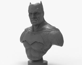 Könnte beinhalten: Graue Batman-Büste, die die Kapuze des Superhelden mit spitzen Ohren und dem Fledermaussymbol auf der Brust zeigt. Die Büste ist auf einem kreisförmigen Sockel montiert und zeigt den strengen Gesichtsausdruck und den muskulösen Körperbau des Charakters.