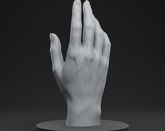 Könnte beinhalten: Eine graue Skulptur einer Hand, wobei der Zeige- und Mittelfinger nach oben gestreckt sind. Die Hand ist auf einem dunkelgrauen kreisförmigen Sockel montiert, vor einem dunklen Hintergrund. Die Skulptur ist detailliert und zeigt die Hautstruktur.