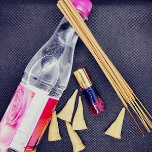 Könnte beinhalten: Ein Set aus Räucherstäbchen, Räucherkegeln, einer Flasche Rosenwasser und einer kleinen Flasche ätherischem Öl. Die Räucherstäbchen sind braun und die Kegel sind beige. Die Rosenwasserflasche ist klar mit einem rosa Deckel. Die Flasche mit ätherischem Öl ist golden mit einer blauen und roten Flüssigkeit darin.