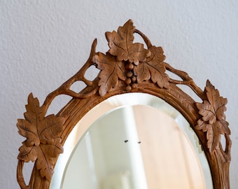 Black forest mirror Antique oval mirror in adirondack frame with carving leaves branches grape vine Carved wood bevelled mirror tabletop