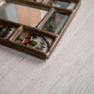 May include: A gold-toned picture frame with a mirror in the centre and multiple smaller picture frames surrounding it. Each frame contains a vintage image.