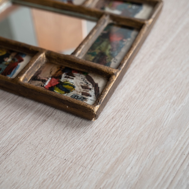 May include: A gold-toned picture frame with a mirror in the centre and multiple smaller picture frames surrounding it. Each frame contains a vintage image.