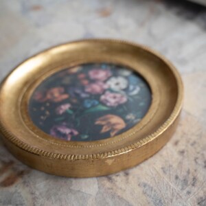 Angled top-down view of the round gold frame lying flat on a surface, highlighting the gilded wooden photo frame finish.