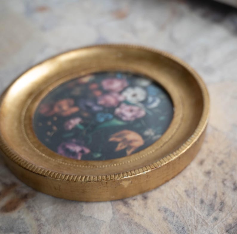 Angled top-down view of the round gold frame lying flat on a surface, highlighting the gilded wooden photo frame finish.
