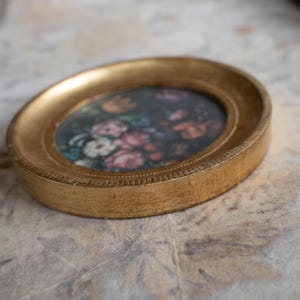 Side profile angle of the round gold frame lying flat, showcasing the thick wooden rim and gilded finish.